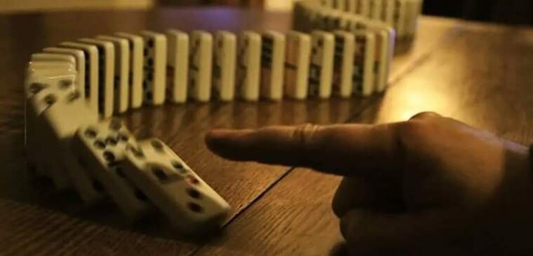 цепочка домино падает, символизируя цепную реакцию на рынке